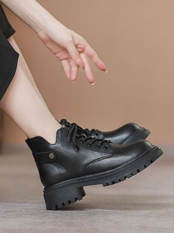 Person lacing up black combat boots with round toe and platform sole while wearing a black skirt._4