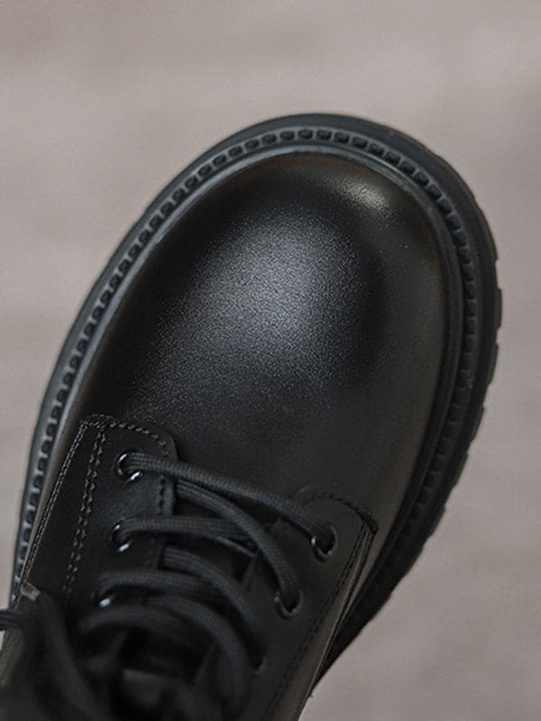 Person lacing up black combat boots with round toe and platform sole while wearing a black skirt._6