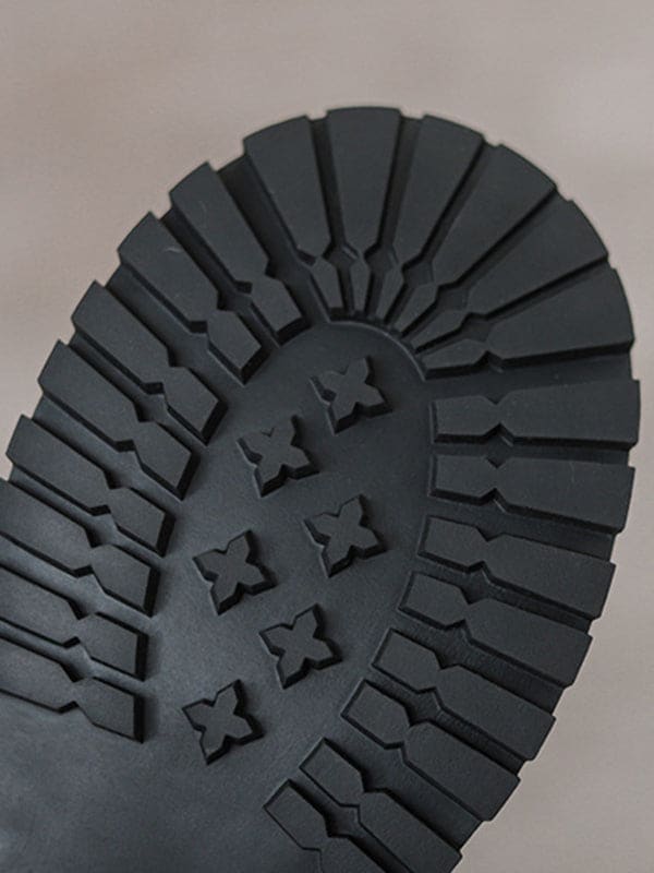 Person lacing up black combat boots with round toe and platform sole while wearing a black skirt._7