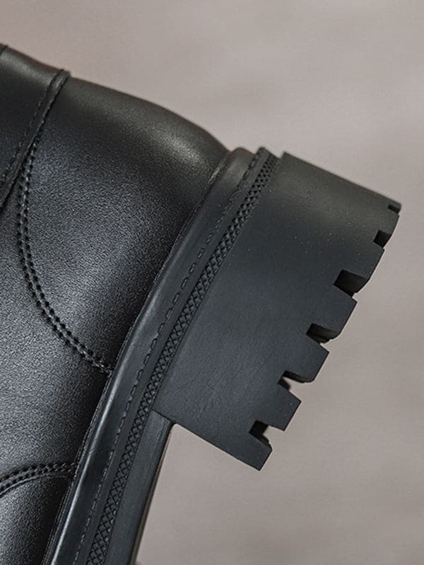 Person lacing up black combat boots with round toe and platform sole while wearing a black skirt._8