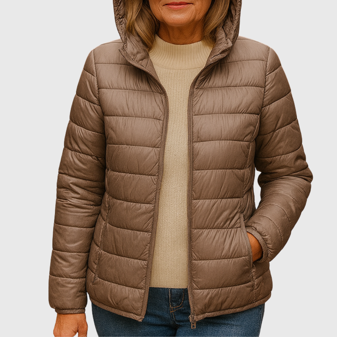Taupe lightweight hooded quilted puffer jacket worn open over a cream sweater, with one hand in a side pocket.