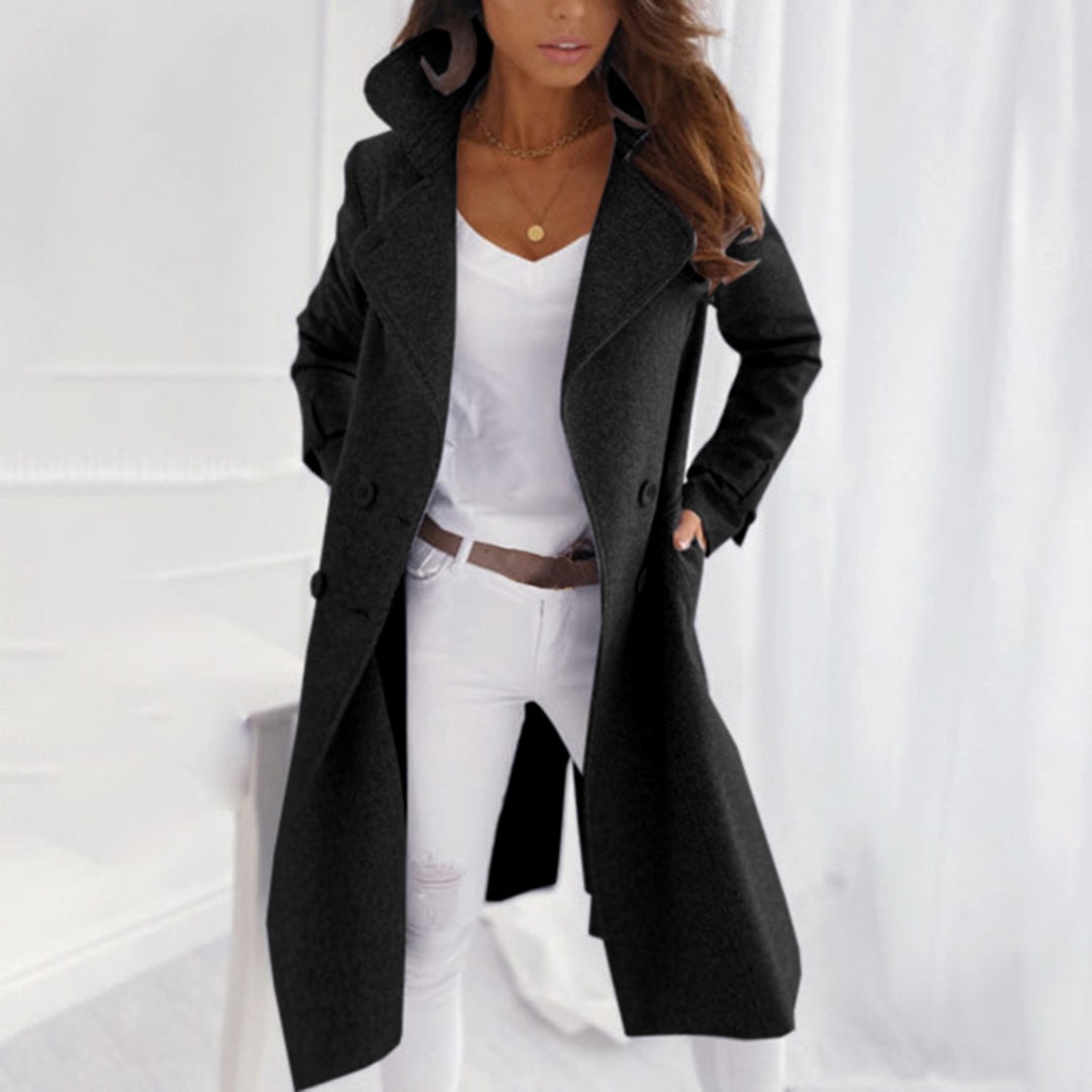 Long black double-breasted coat with a notched collar, long sleeves, and side pockets styled with white jeans.