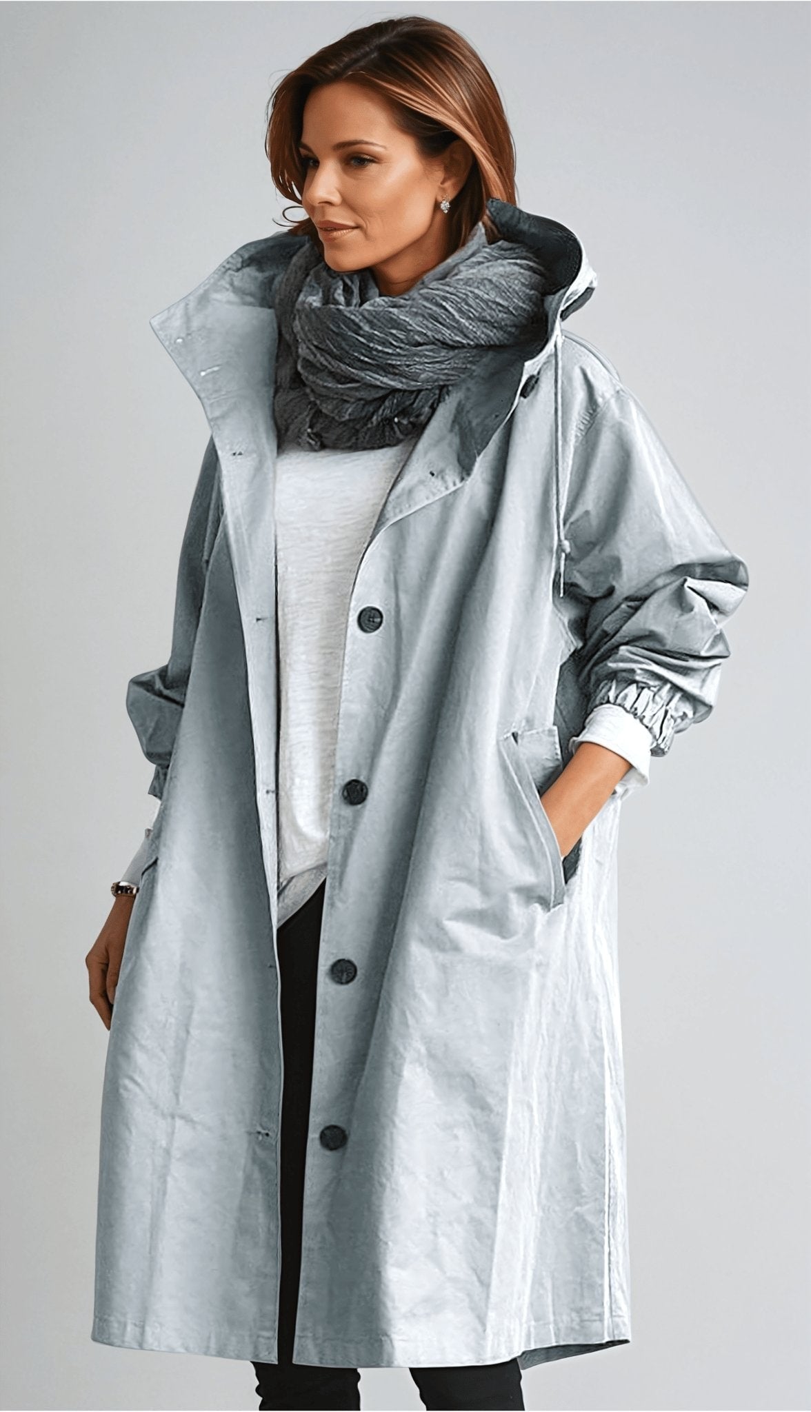 Light gray long hooded coat worn open over a light top, with a button front, side pockets, and rolled adjustable cuffs.