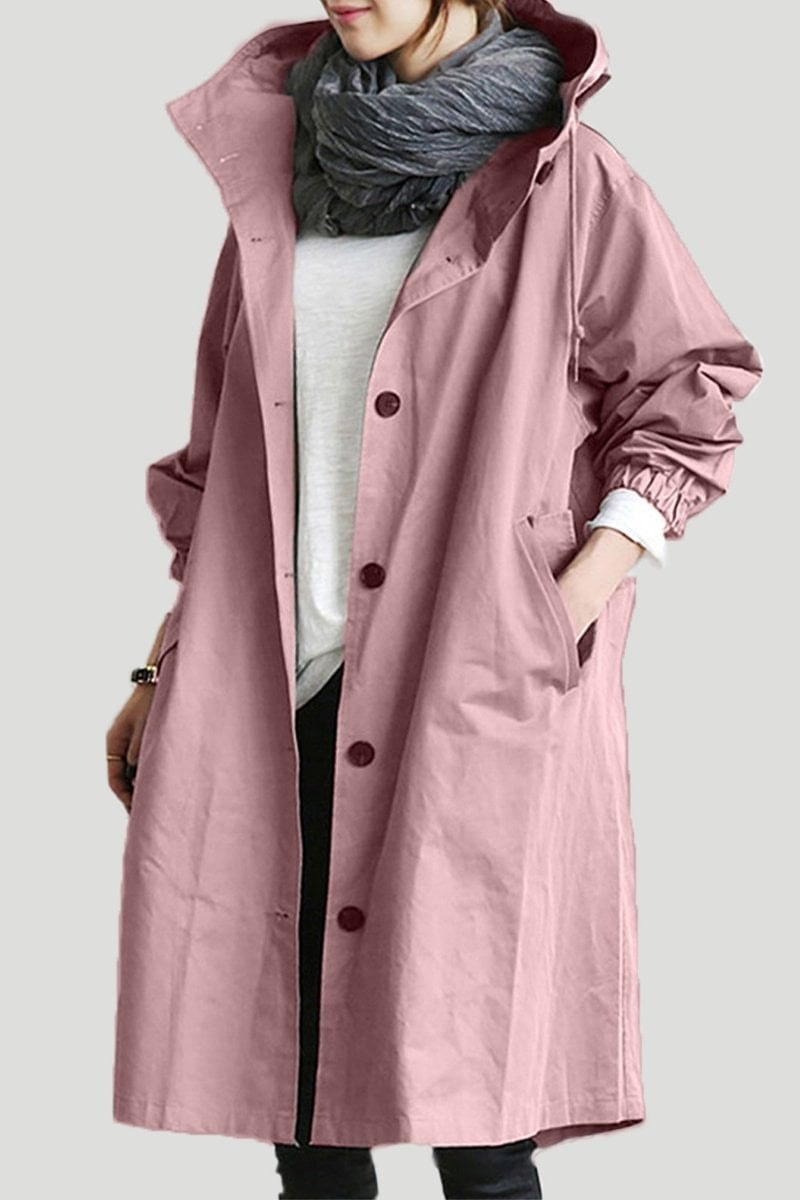 Dusty pink long hooded coat worn over casual layers, showing the dark front buttons, pointed hood, side pockets, and long silhouette.