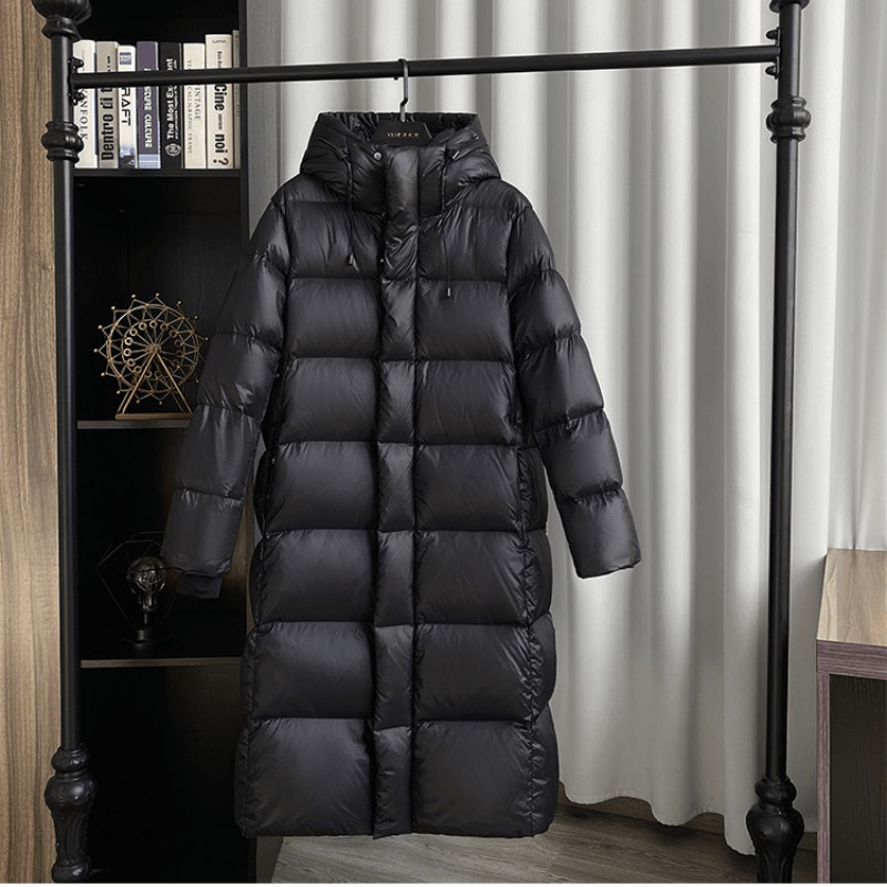 Hanging front view showing the jacket’s hood, sleeves, long quilted body, and front closure.