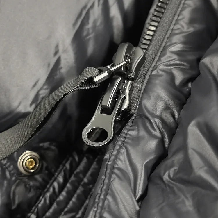 Close-up showing the jacket’s front zipper slider, zipper teeth, and adjacent snap fastener.