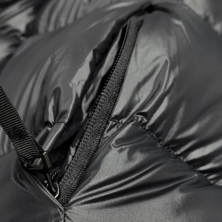 Close-up of a black zipper and attached strap detail on the quilted jacket.