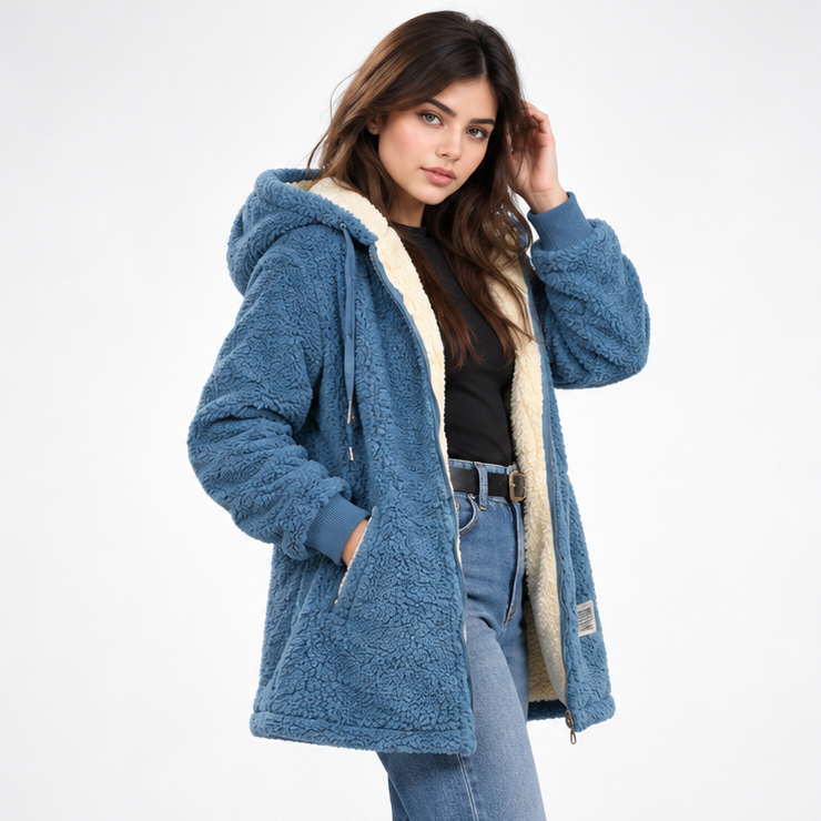 Three-quarter view of the blue hooded teddy jacket with its cream-lined interior, open front zip, and hand in a front pocket.