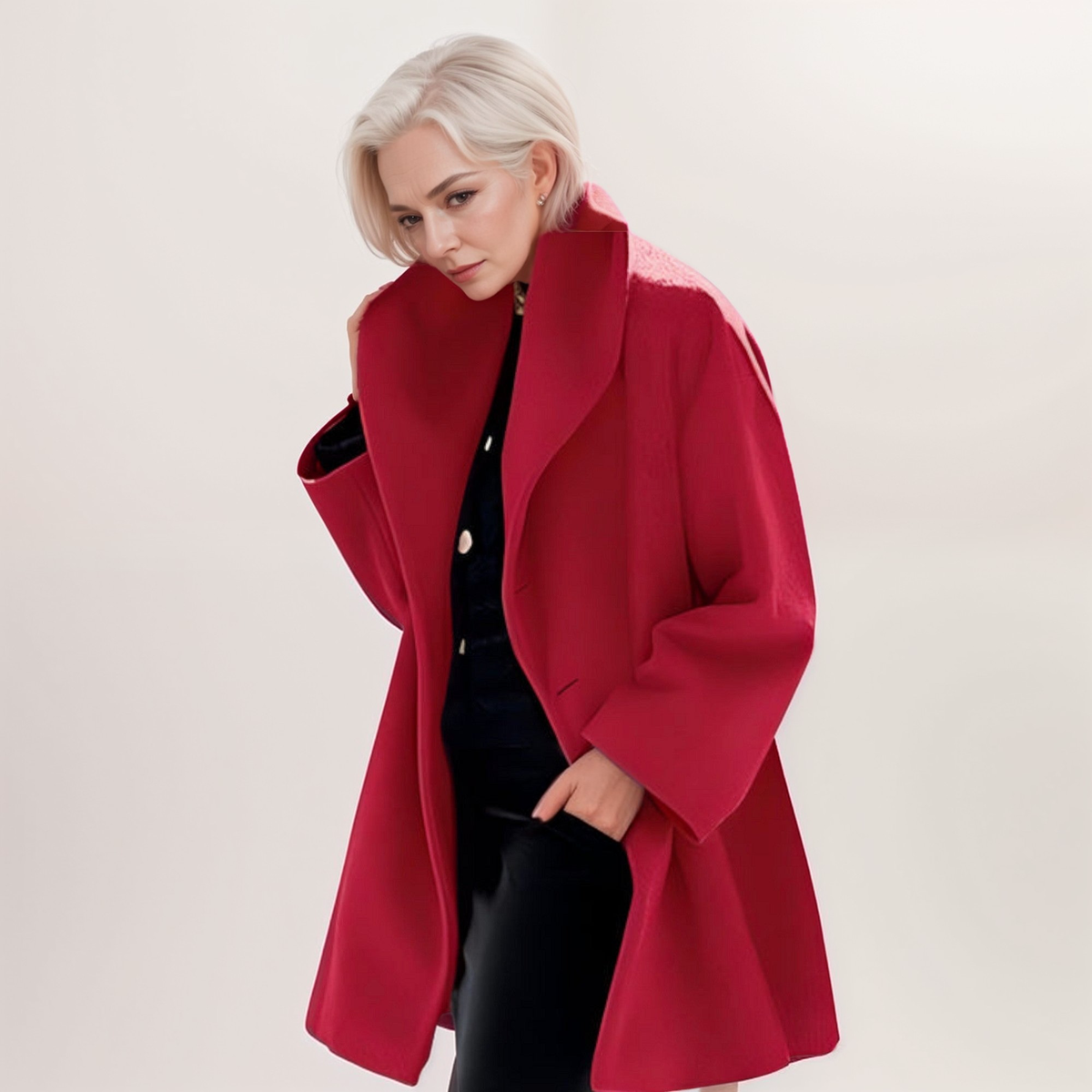 Bright red longline coat featuring a broad folded collar, roomy sleeves, and an open front over black clothing.