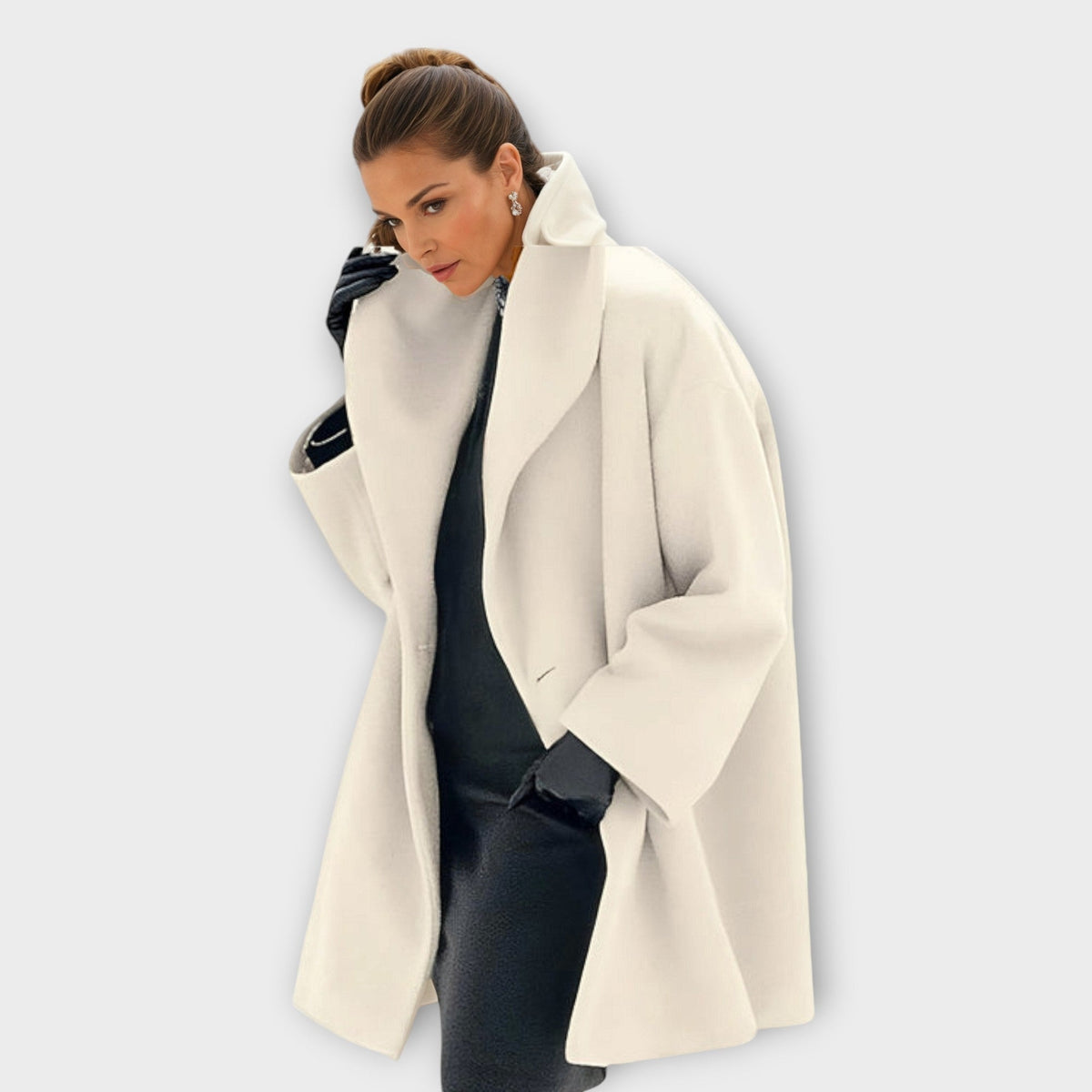 Ivory longline coat worn over a dark outfit, highlighting the oversized collar, open front, and relaxed sleeves.