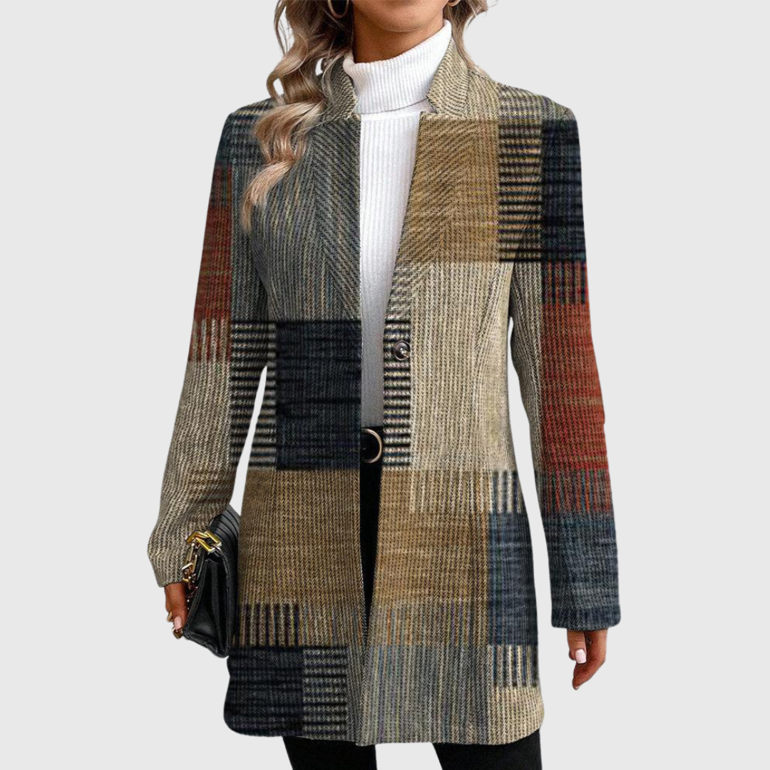 Long patchwork plaid blazer with a notched lapel, single-button front, and contrasting gray, brown, black, and rust plaid panels, styled over a white turtleneck.