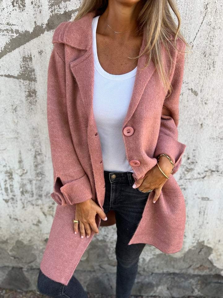 Pink longline button-front blazer jacket worn open over a white top, with notched lapels and rolled cuffs.