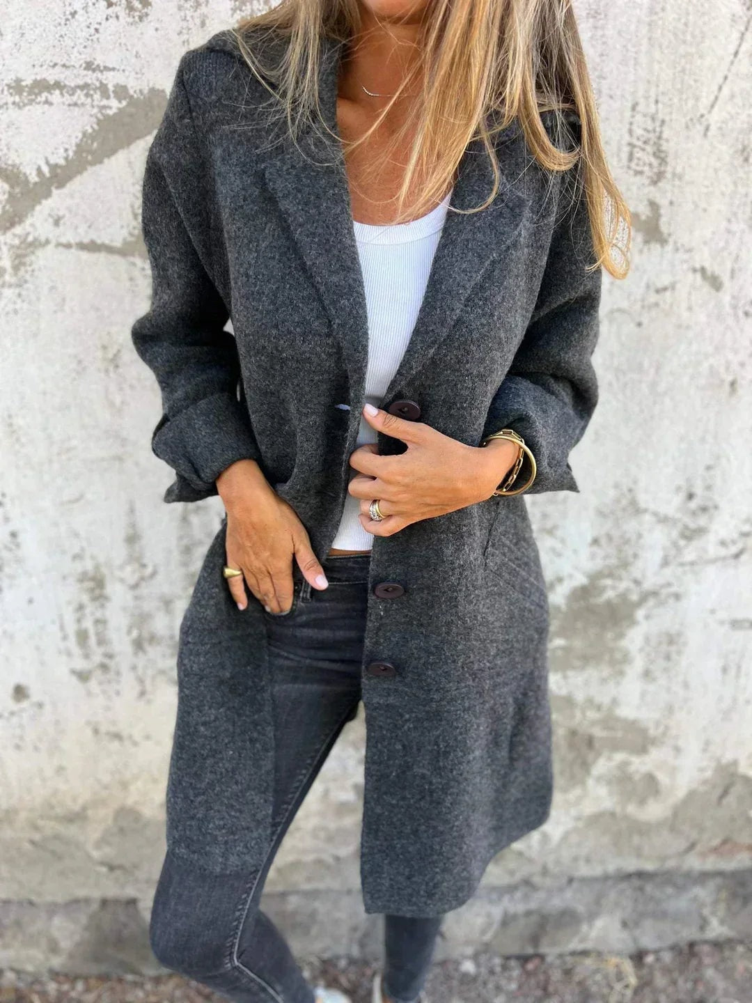 Charcoal gray longline blazer jacket worn over a white top, showing notched lapels and a partially fastened front.