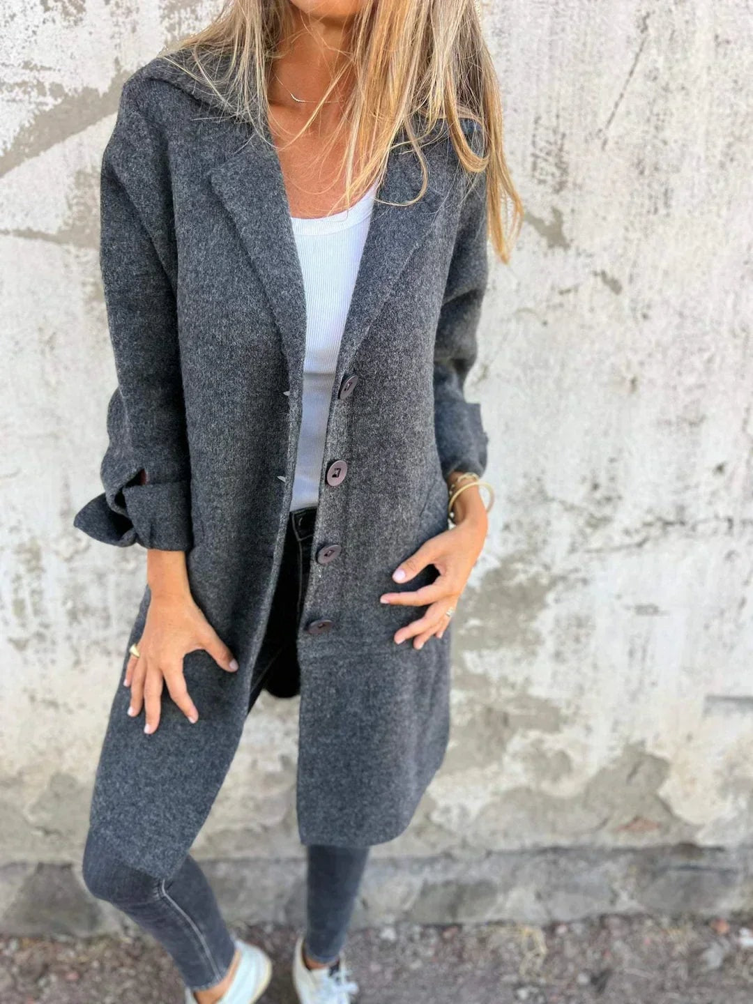 Side-angled view of the charcoal gray blazer jacket with its long hem, button front, and rolled sleeve cuffs.