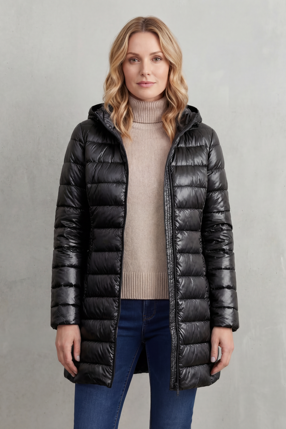 Front view of the black hooded puffer jacket worn open over a beige sweater, showing its long coverage and quilted design.