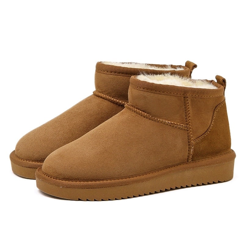 Pair of tan low ankle snow boots displayed against white, highlighting the rounded toes, raised platform soles, and textured outsoles.