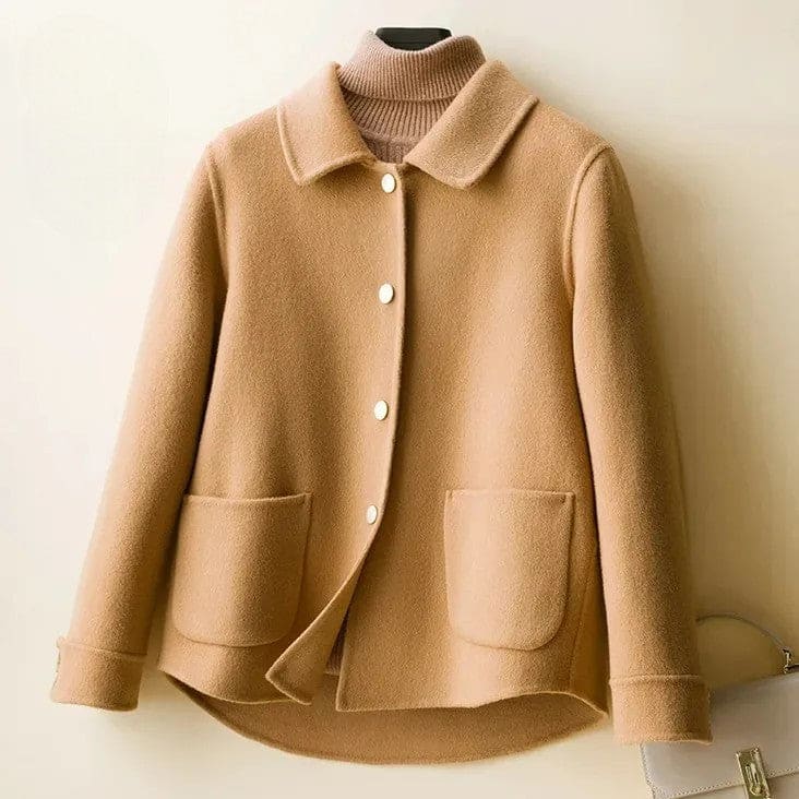 A short coat with a rounded collar, front snap buttons, and curved patch pockets displayed over a ribbed high-neck top._0
