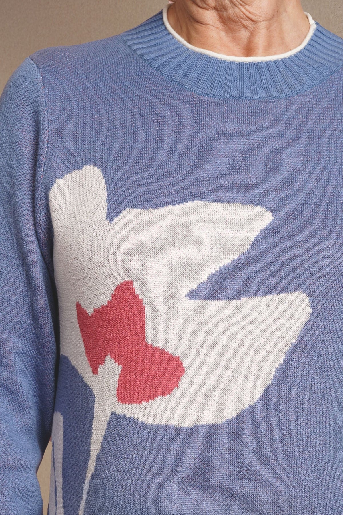 Woman wearing a long sleeve crew neck knit jumper with a large intarsia flower motif on the front, ribbed neckline, cuffs and hem, with trousers._2