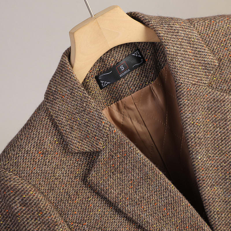 A tailored speckled blazer with notched lapels, a single button front, and front patch pockets displayed on a hanger._3