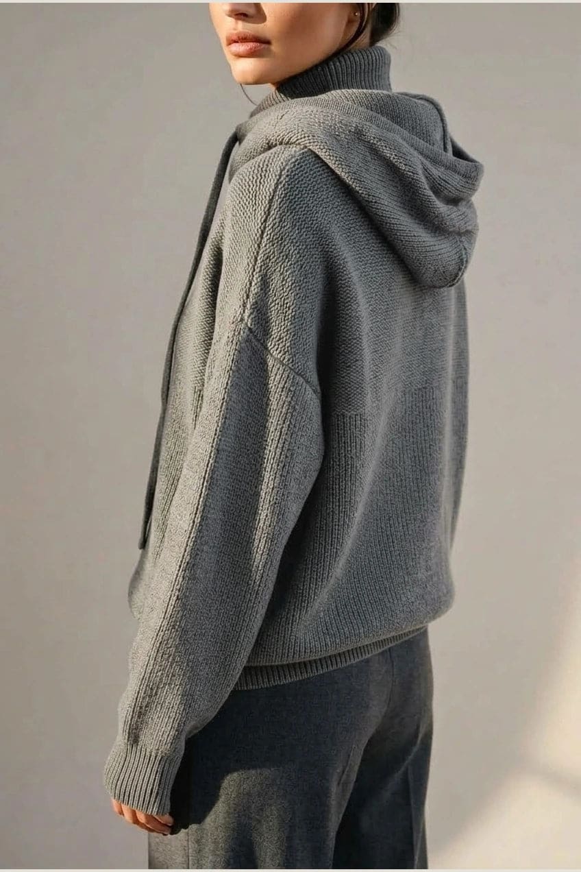 Woman wearing an oversized knitted hooded jumper with drawstring, dropped shoulders and a deep ribbed hem, with straight trousers and trainers._5