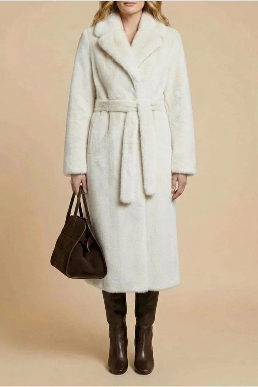Woman wearing a long belted faux fur coat with notch lapels, tie waist and full-length sleeves, holding a suede tote and wearing knee-high boots._1