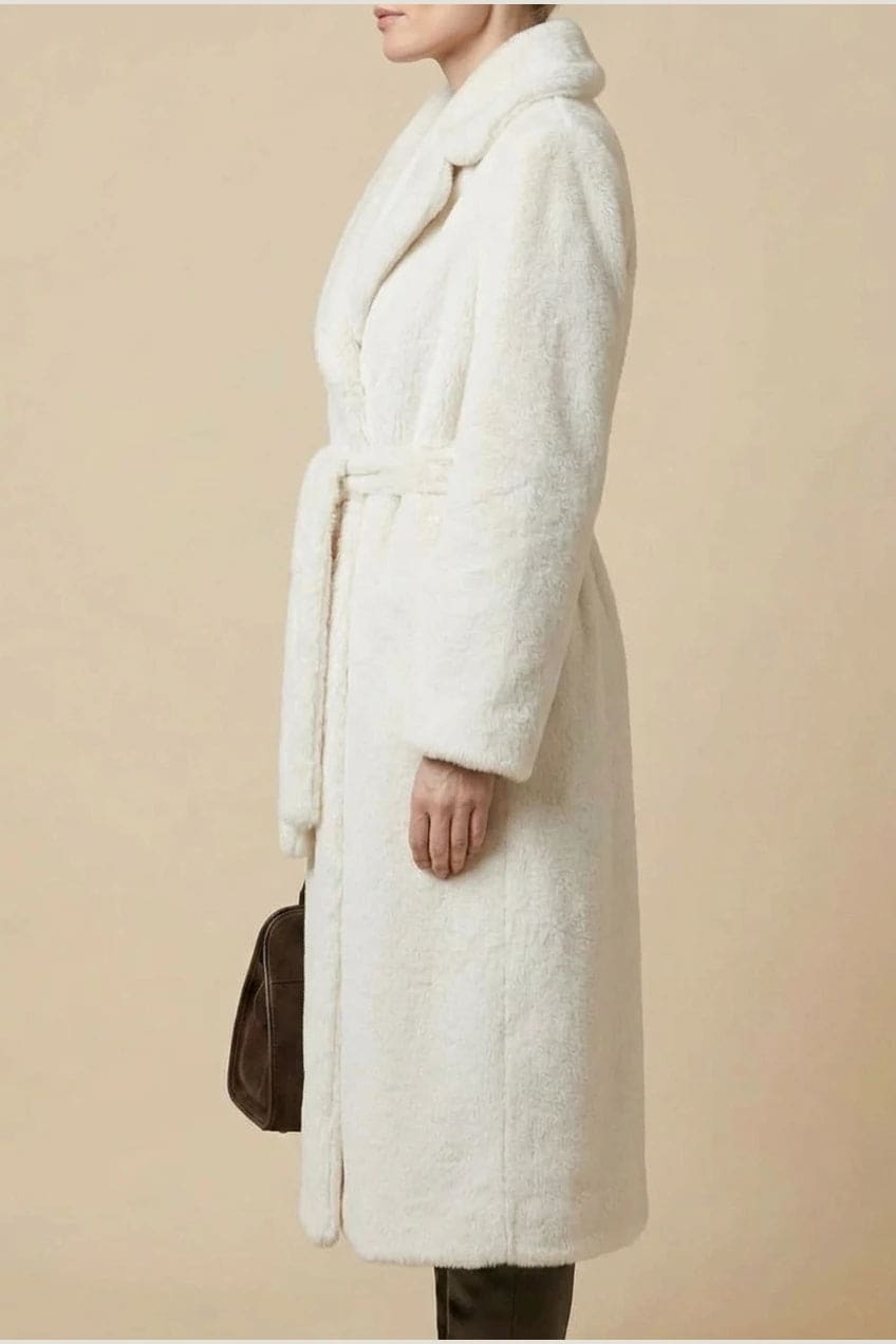 Woman wearing a long belted faux fur coat with notch lapels, tie waist and full-length sleeves, holding a suede tote and wearing knee-high boots._5