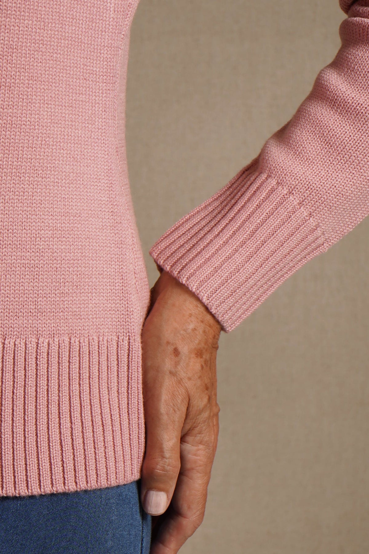 Woman seated wearing a long sleeve knit cardigan with round neck, full button front and ribbed cuffs and hem, with jeans._2