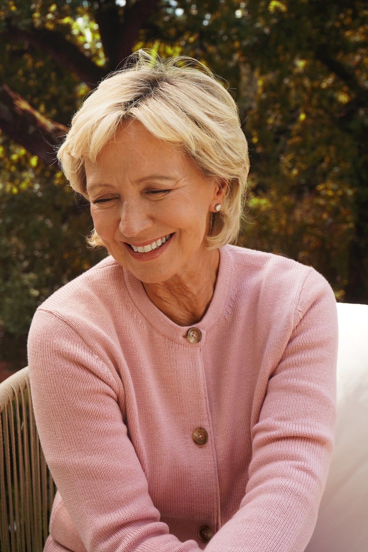 Woman seated wearing a long sleeve knit cardigan with round neck, full button front and ribbed cuffs and hem, with jeans._4
