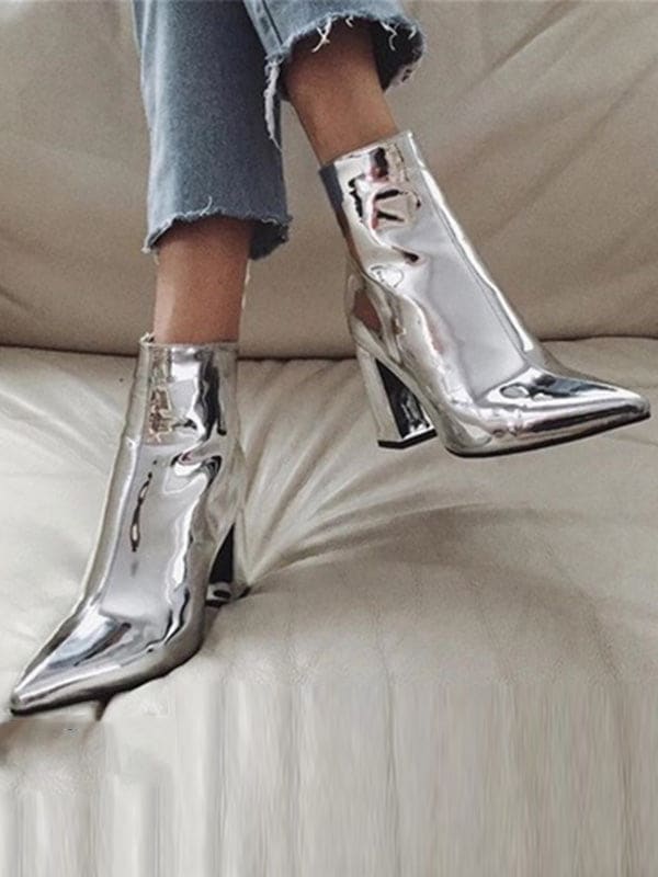 Metallic silver ankle boots with pointed toe and block heel worn with cropped jeans on a neutral surface_0