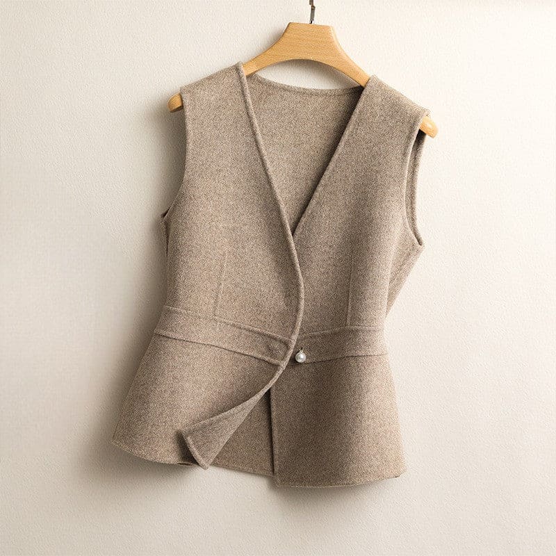 A sleeveless wrap vest with a V neckline, defined waist seam, and single front button displayed on a wooden hanger._0