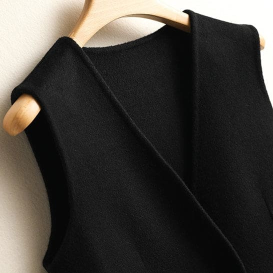 A sleeveless wrap vest with a V neckline, defined waist seam, and single front button displayed on a wooden hanger._4