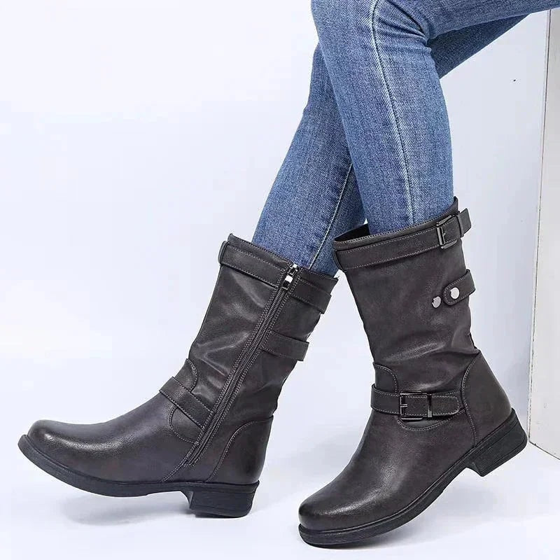 Black mid-calf boots displayed from the side, highlighting the vertical zippers, ankle buckles, and upper shaft straps.