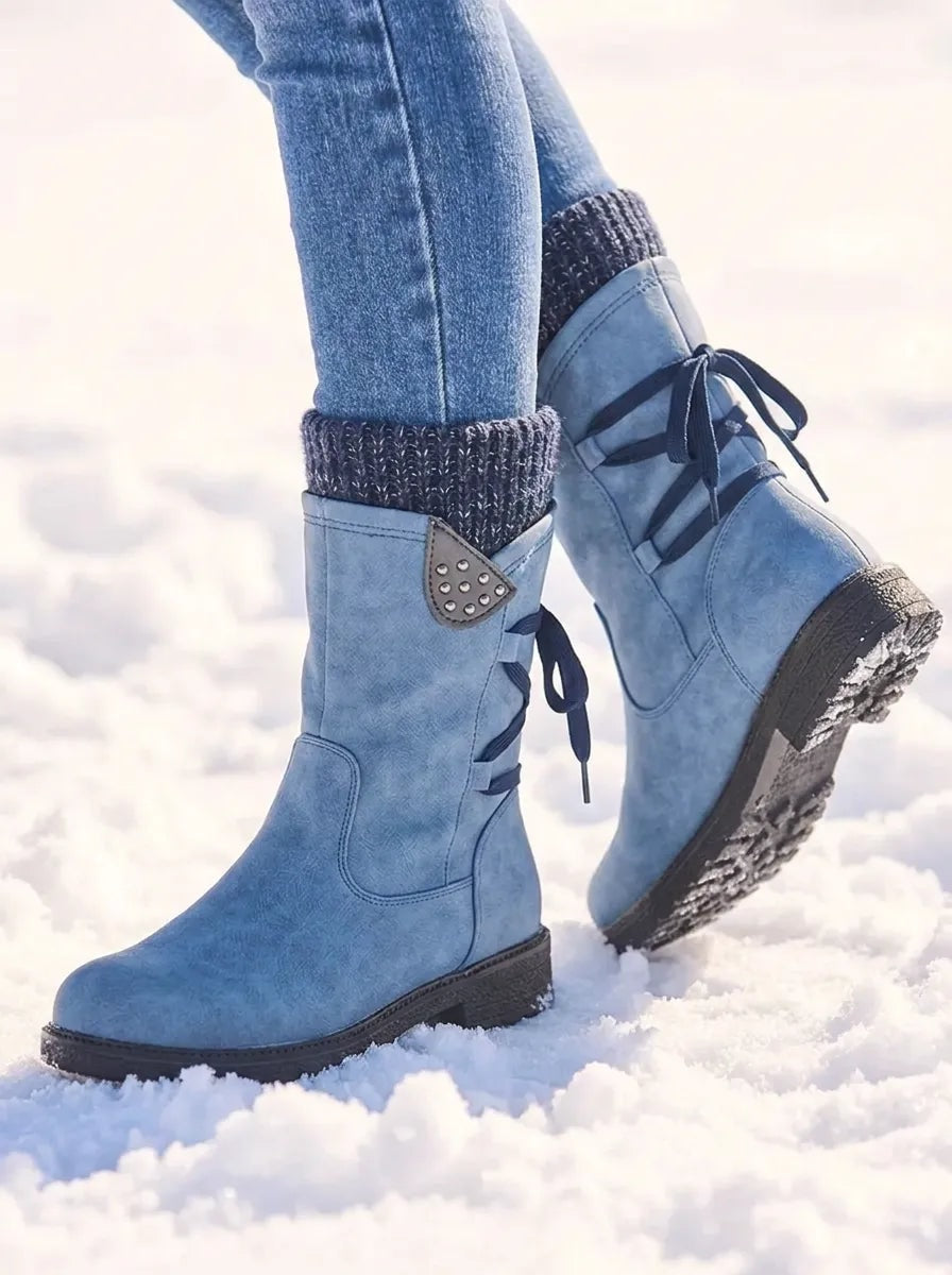 Light blue winter boots shown from the rear side, with one boot raised to reveal the textured tread and decorative side accents.