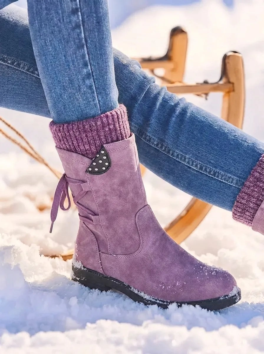 Mauve purple mid-calf winter boot standing in snow, with a matching knitted cuff, side zip and studded decorative tab.