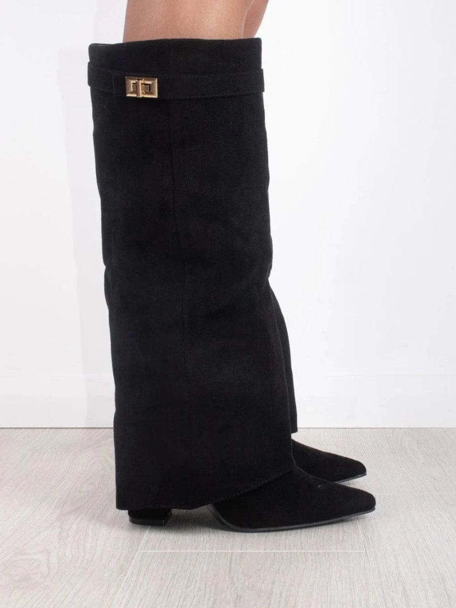 Black fold-over knee-high boots standing side by side on a light floor, with pointed toes and low heels visible.