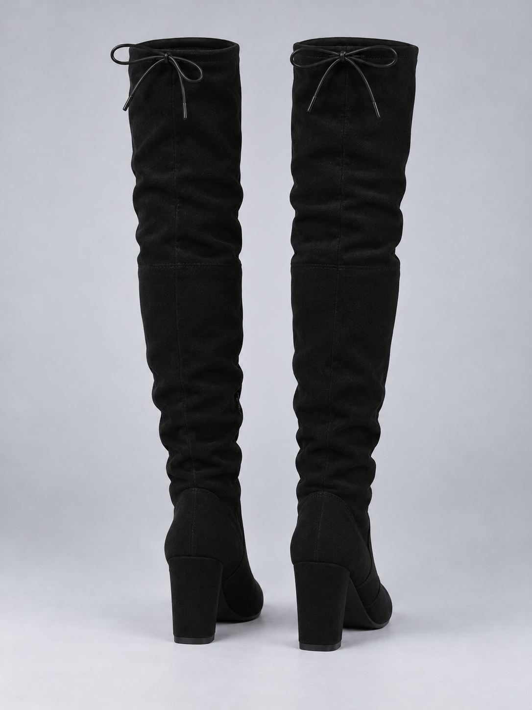 Rear view of black over-the-knee boots showing the tied shaft details, gathered panels, and block heels.