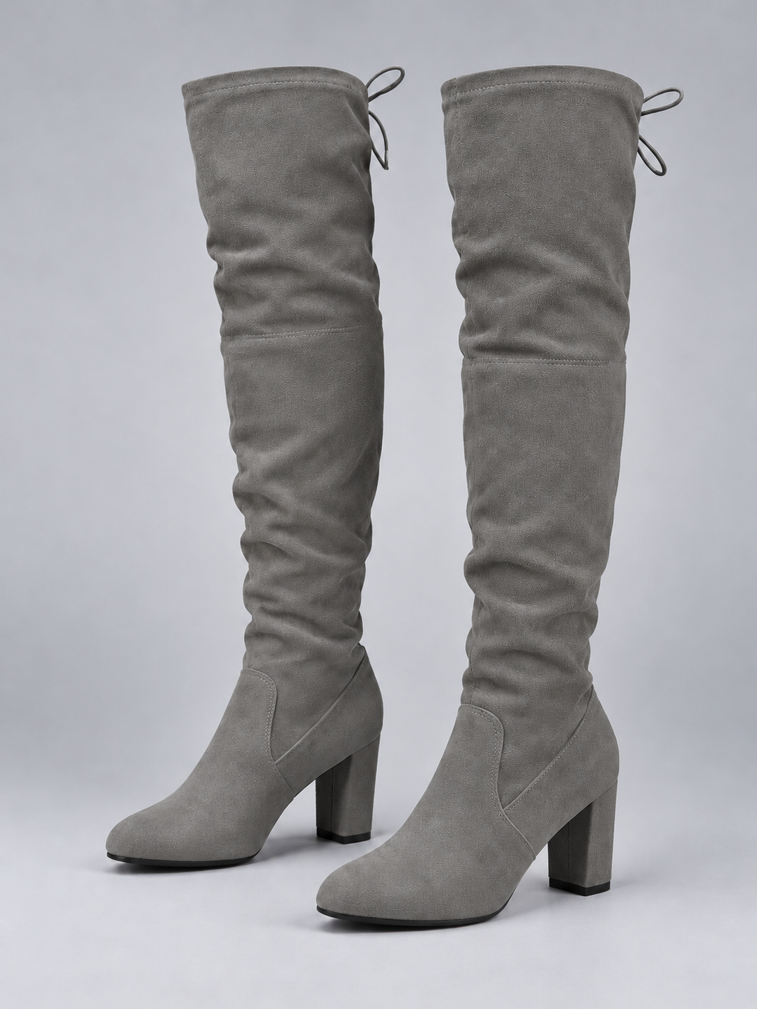 Pair of gray over-the-knee boots with gathered shafts, rounded toes, rear tie details, and tall block heels shown from the front and side.