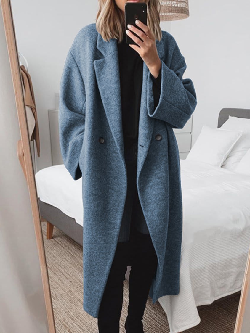 Longline oversized coat with notched lapels, drop shoulders and two front buttons, worn open over a dark top and trousers._0
