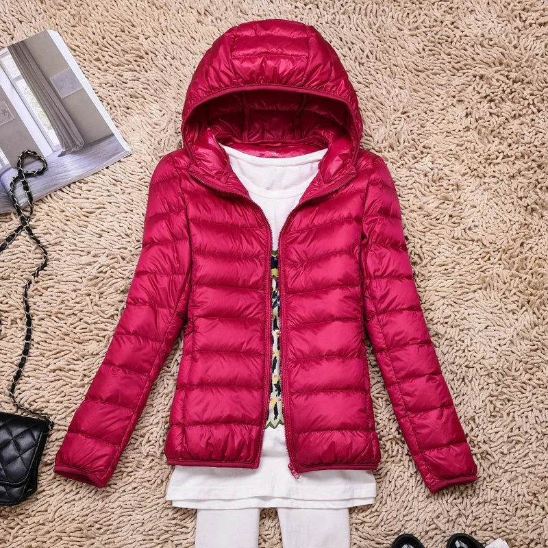 Bright pink hooded puffer jacket laid flat with its open front revealing a layered outfit.