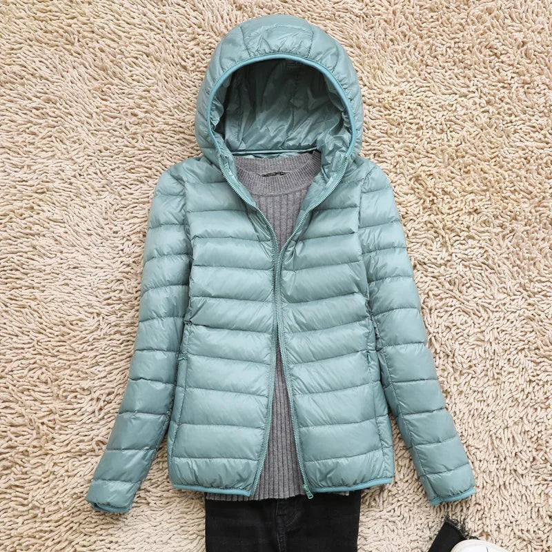 Light blue hooded puffer jacket shown open and laid flat over a gray knit top.