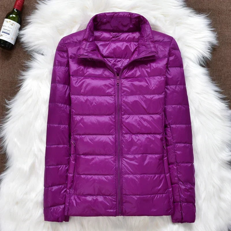 Purple quilted puffer jacket shown zipped with a raised stand collar.