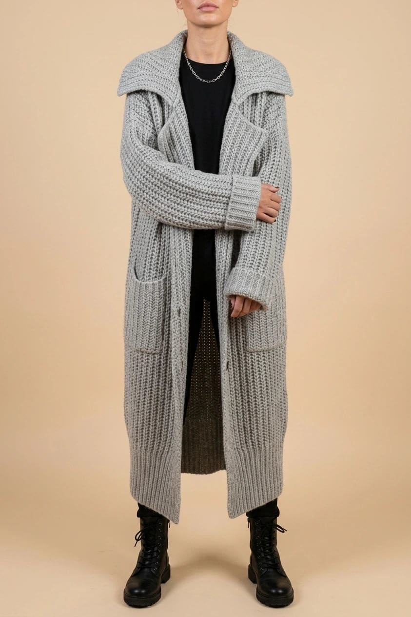 Woman wearing a long open front chunky rib knit cardigan with an oversized fold over collar, two patch pockets and ribbed cuffs, over a top and trousers with lace up boots._0