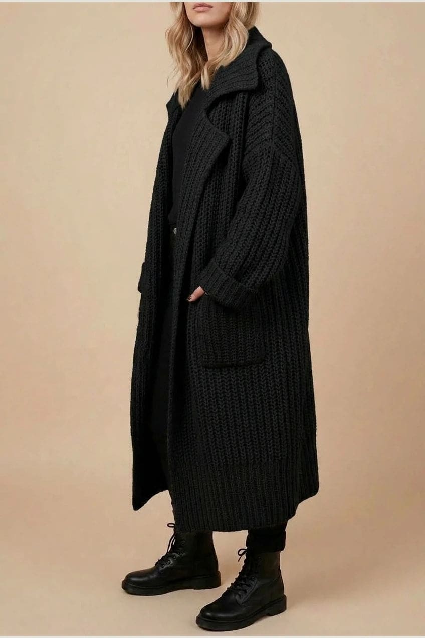 Woman wearing a long open front chunky rib knit cardigan with an oversized fold over collar, two patch pockets and ribbed cuffs, over a top and trousers with lace up boots._2