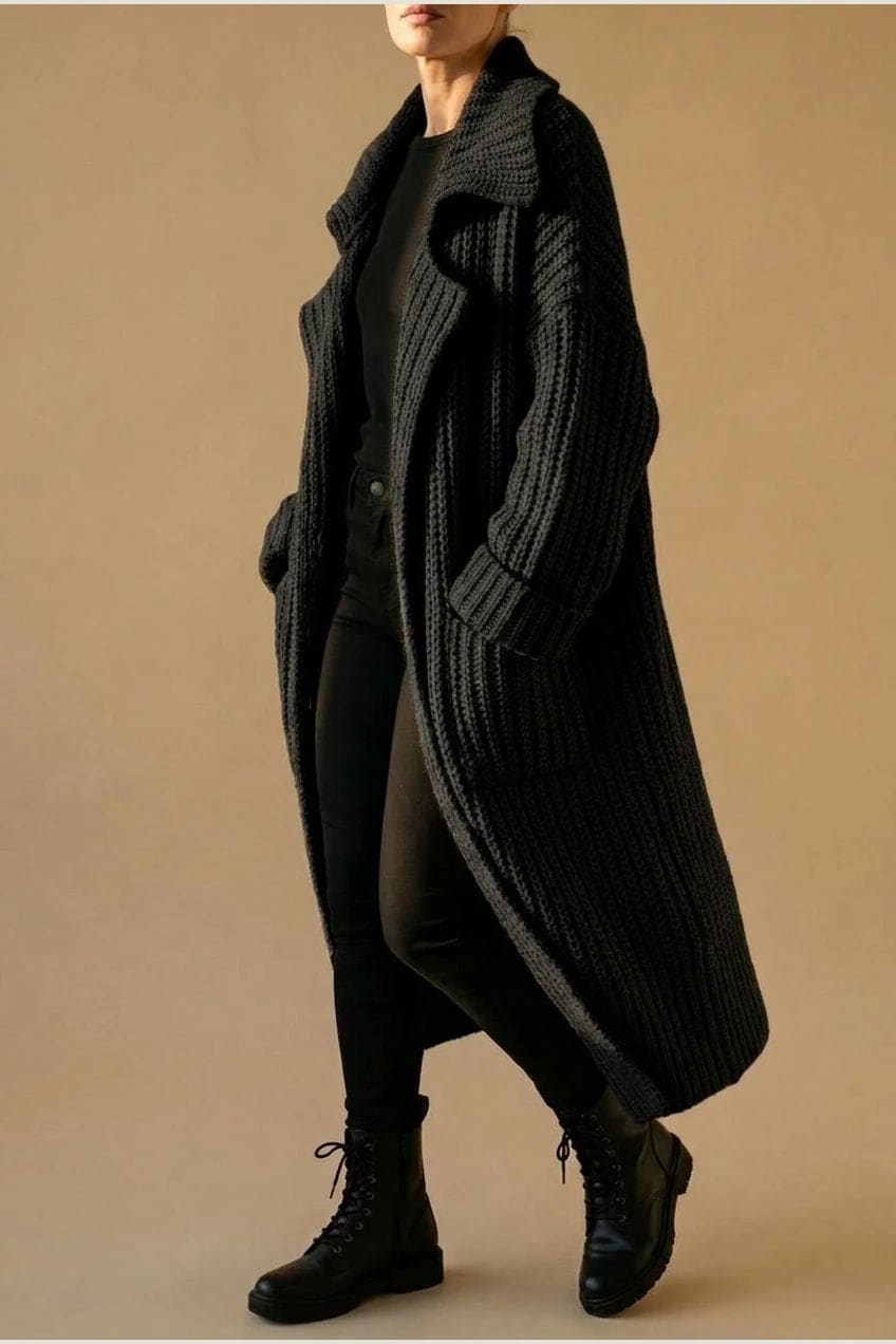 Woman wearing a long open front chunky rib knit cardigan with an oversized fold over collar, two patch pockets and ribbed cuffs, over a top and trousers with lace up boots._3