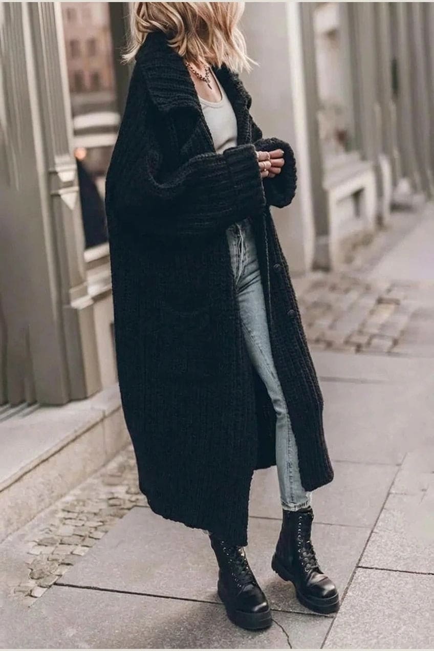 Woman wearing a long open front chunky rib knit cardigan with an oversized fold over collar, two patch pockets and ribbed cuffs, over a top and trousers with lace up boots._4