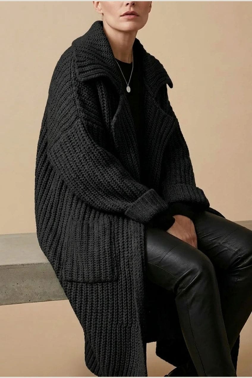 Woman wearing a long open front chunky rib knit cardigan with an oversized fold over collar, two patch pockets and ribbed cuffs, over a top and trousers with lace up boots._5