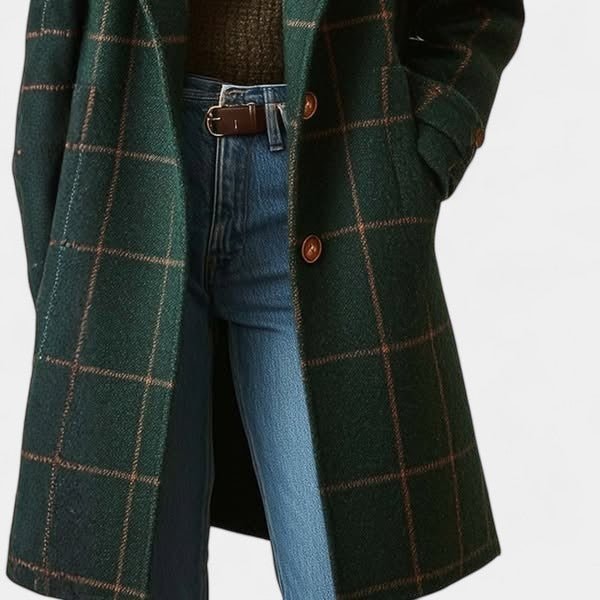 Detail of the green plaid coat extending over blue jeans, showing the lower front, brown button closure, and mid-thigh length.