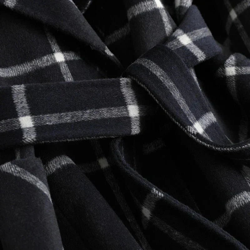 Close detail of the black plaid coat's checked pattern, overlapping front panels, and sleeve cuff.