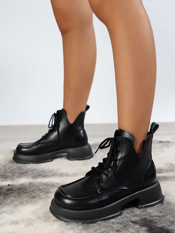 Pair of platform lace-up boots with chunky sole and round toe displayed on a geometric white stand._2