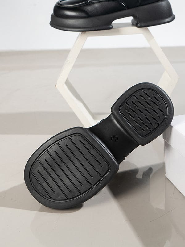 Pair of platform lace-up boots with chunky sole and round toe displayed on a geometric white stand._4